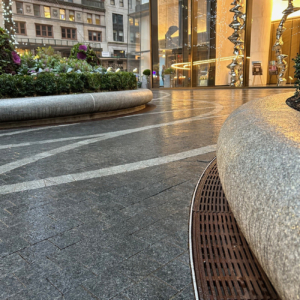 Cast iron radius drain grate in linear Que pattern, shown at base of large planters in One Vanderbilt Plaza