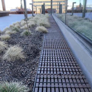 Cast iron trench drain grate in linear Plex pattern. Shown in rooftop garden.
