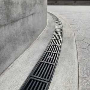 Cast iron radius trench drain grates in a linear Que pattern, black powder coat finish.