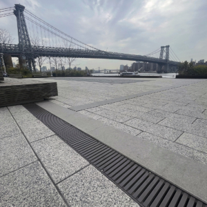 Cast iron trench drain grates in linear Regular Joe pattern, with Brooklyn Bridge in the background
