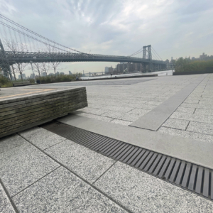 Cast iron trench drain grates in linear Regular Joe pattern, with Brooklyn Bridge in the background