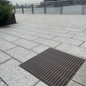 Cast iron drain grates in linear Regular Joe pattern, with Brooklyn Bridge in the background